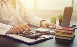 Physician entering billing data into laptop computer