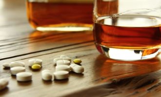 Pills and glass of alcohol on wood table