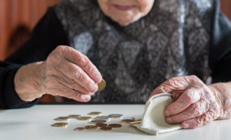 An elderly woman sitting at the table counting money in her wallet