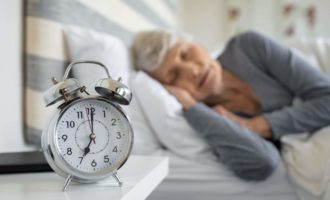 Closeup of a clock and a woman sleeping