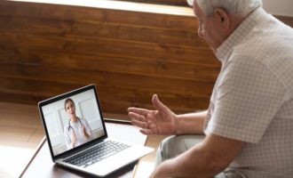 Older male patient consulting with doctor via video call.