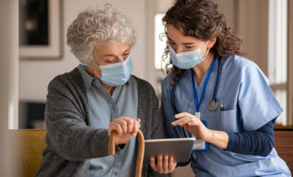 Senior woman and nurse using digital tablet at home during consult