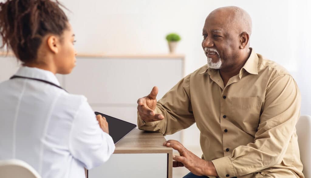 An elderly patient is talking to a young practitioner